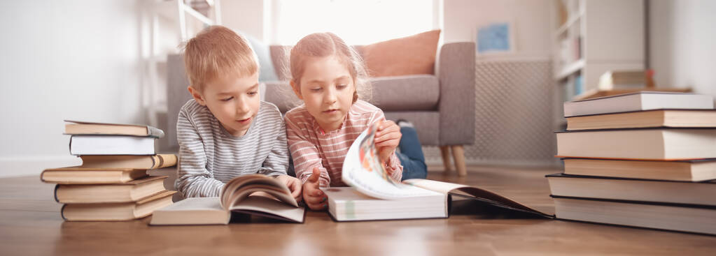 Tatlı çocuklar yere yatıp kitap okuyorlar. - Fotoğraf, Görsel