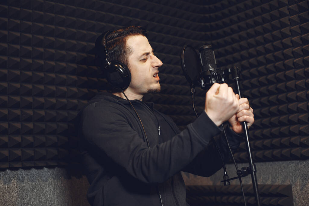 Bir stüdyoda mikrofonla şarkı söylemek ve çalışmak. - Fotoğraf, Görsel