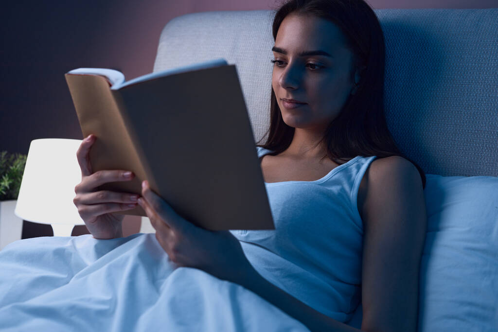 Kobieta czyta książkę w łóżku - Zdjęcie, obraz