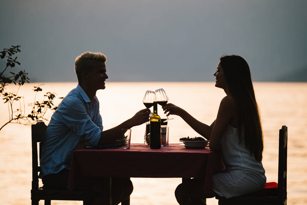 Молодая пара делит романтический ужин на закате на тропическом курорте - Фото, изображение
