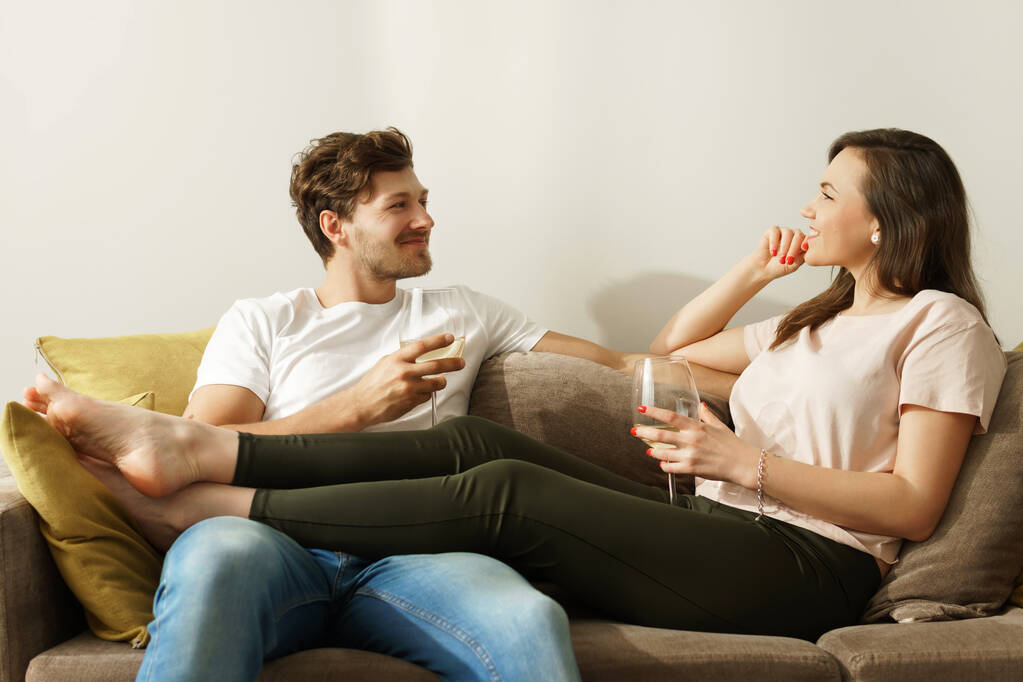 若く幸せなカップルはワインを飲み、自宅でリラックス - 写真・画像