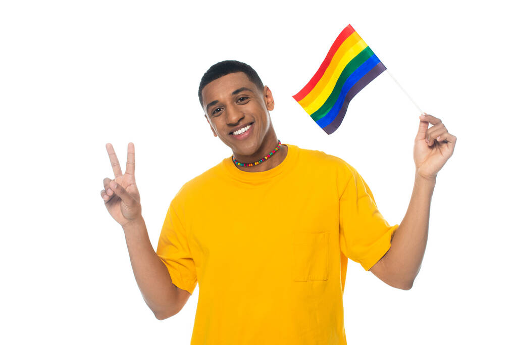 vreugdevolle Afro-Amerikaanse man met lgbt vlag, toont vrede teken geïsoleerd op wit - Foto, afbeelding