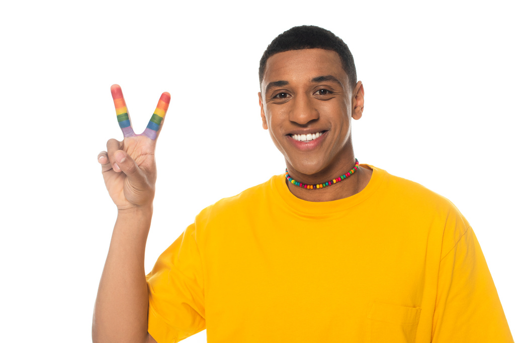 счастливый африканский американец показывает знак мира с пальцами окрашены в цвета lgbt изолированы на белом - Фото, изображение