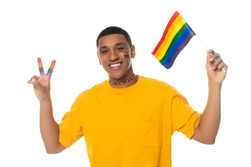 hombre afroamericano feliz sosteniendo bandera lgbt y mostrando signo de victoria aislado en blanco - Foto, imagen