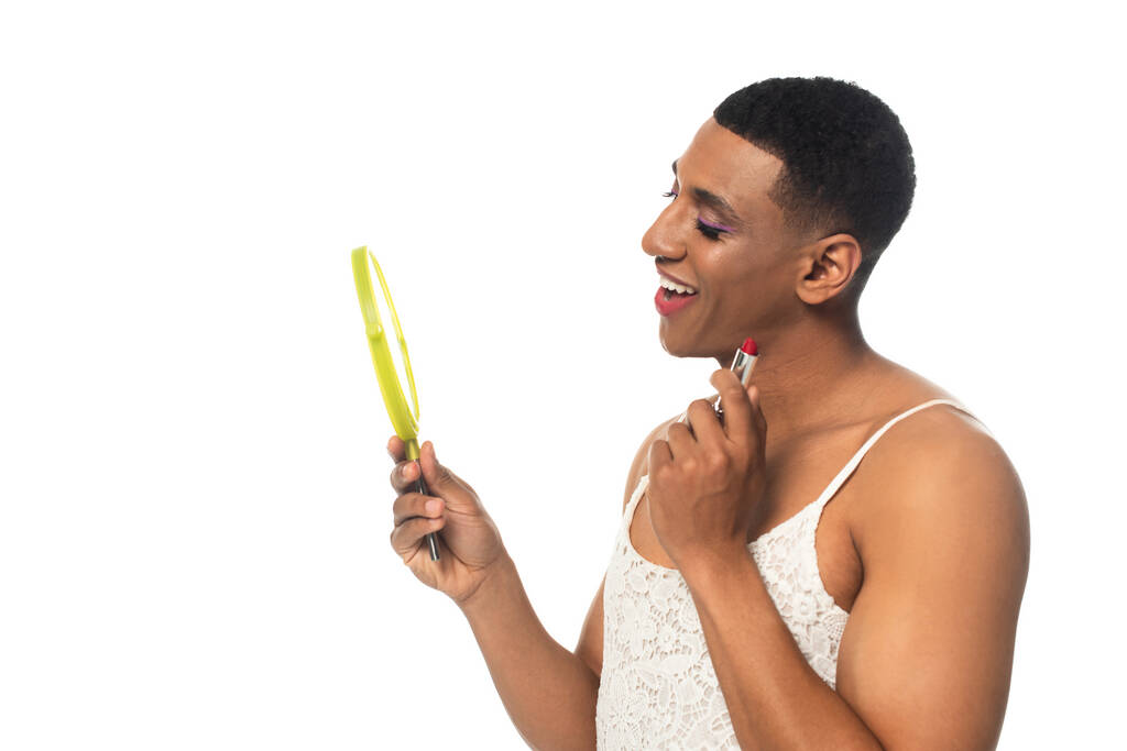 アフリカ系アメリカ人の性転換男性は白で隔離された口紅と鏡を持ちながら笑っています - 写真・画像