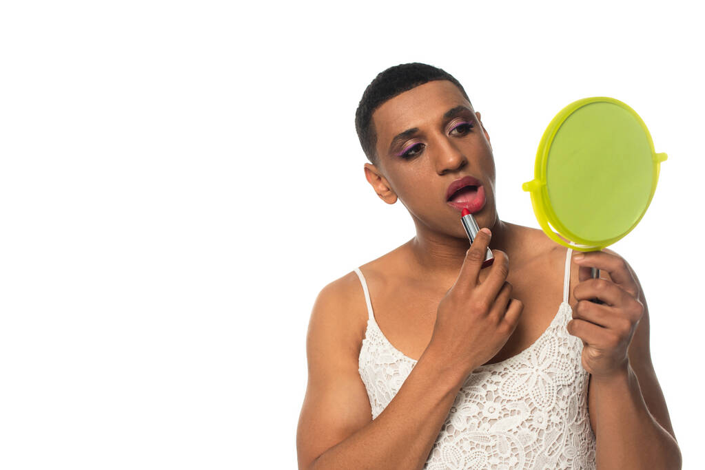 afro-amerikai transznemű férfi sundress tükör és alkalmazása rúzs elszigetelt fehér - Fotó, kép