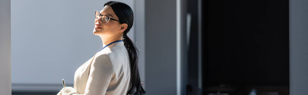 Souriant asiatique femme d'affaires en tenue formelle stylo dans le bureau, bannière  - Photo, image