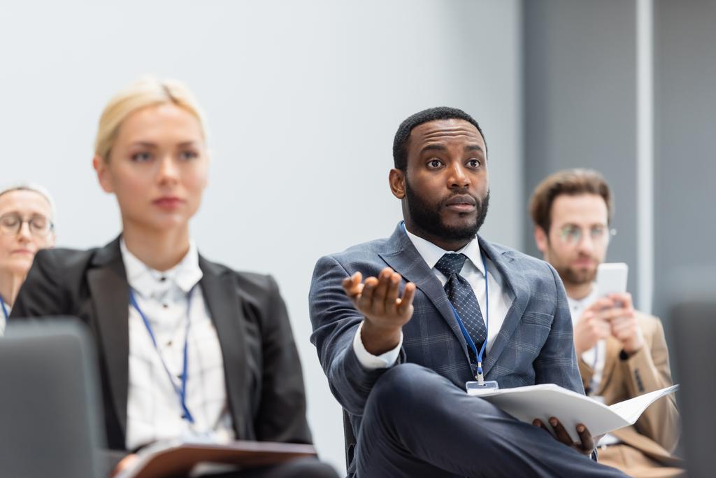 Африканский американский бизнесмен с бумагами, указывающими рукой во время встречи в конференц-зале  - Фото, изображение