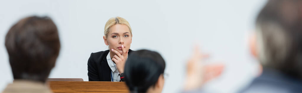 Düşünceli konuşmacı iş konferansı sırasında bulanık seyirciye bakıyor. - Fotoğraf, Görsel