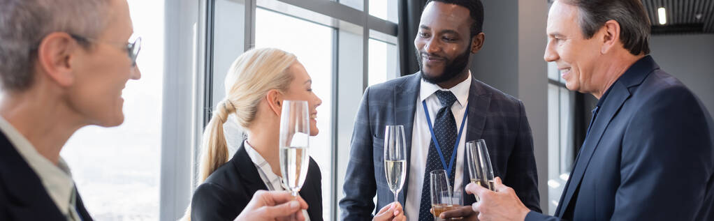 multietničtí podnikatelé držící sklenice šampaňského během diskuse o konferenci, banner - Fotografie, Obrázek