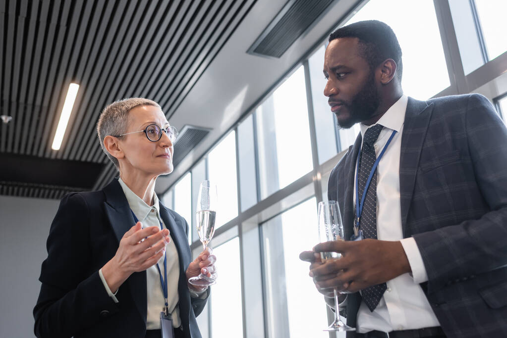 interracial colleagues with champagne glasses talking during business conference - Photo, Image