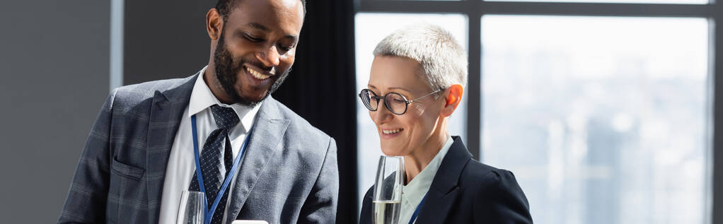 souriant multiethnique hommes d'affaires souriant tout en parlant au bureau, bannière - Photo, image