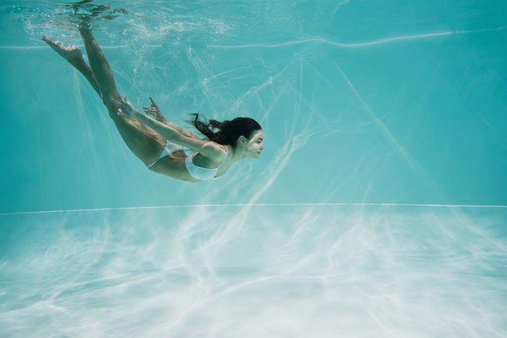 mooie vrouw in wit badpak duiken in zwembad  - Foto, afbeelding