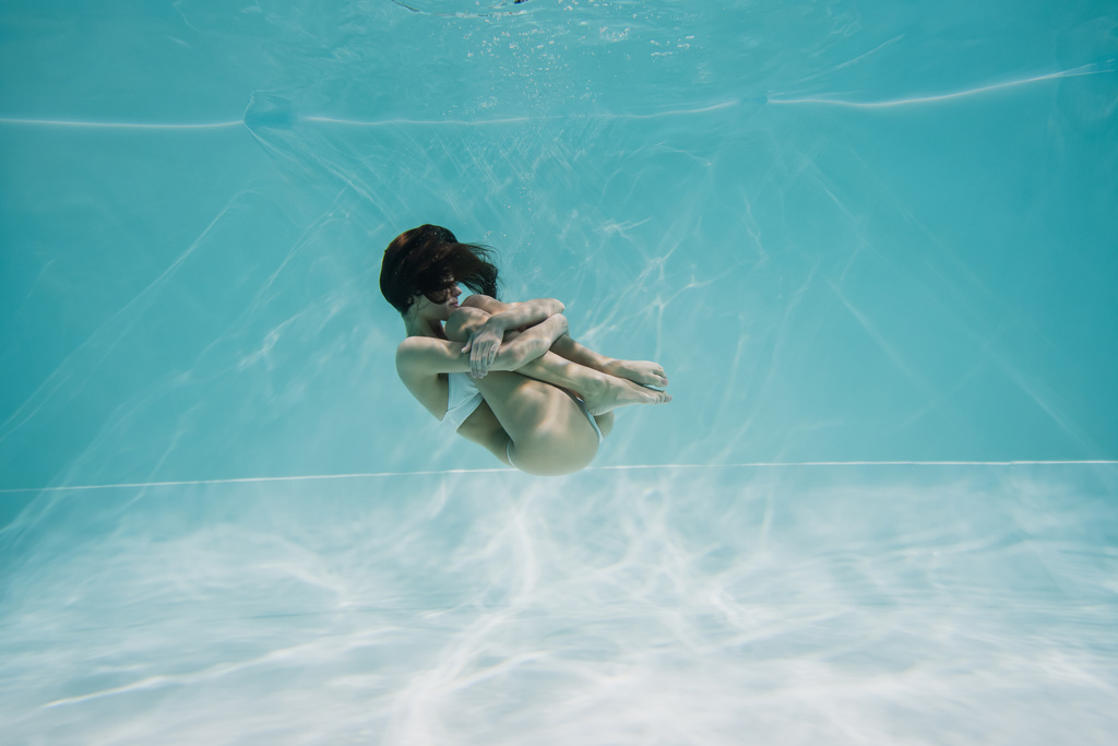 平和的なブルネットの女性で白い水着プールで泳ぐ  - 写真・画像