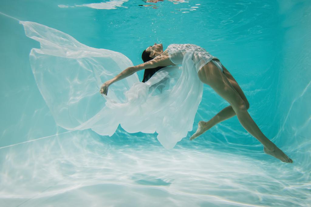 descalça jovem mulher em vestido de mergulho na piscina com água azul  - Foto, Imagem