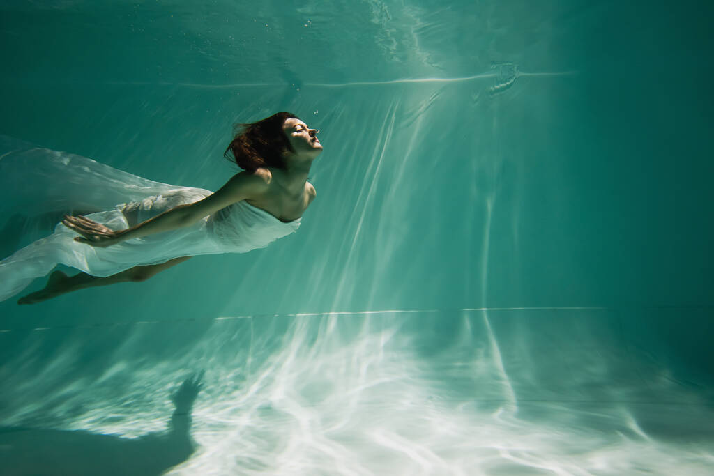 barna fiatal nő fehér elegáns ruha úszás medencében  - Fotó, kép