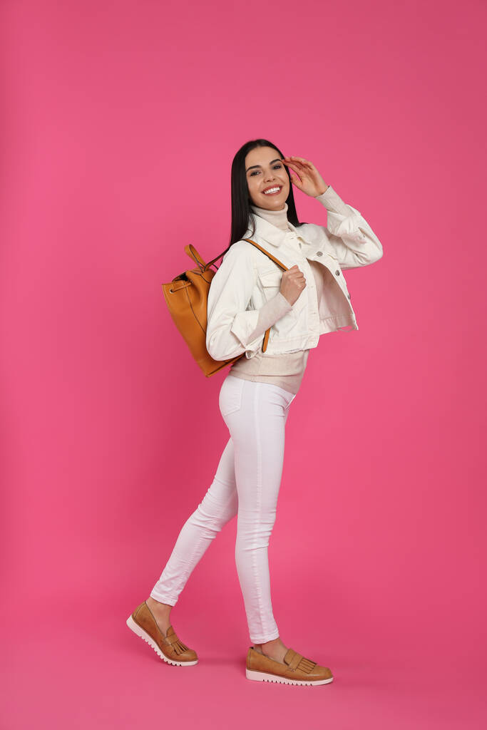 Junge Frau mit stylischem Rucksack auf rosa Hintergrund - Foto, Bild