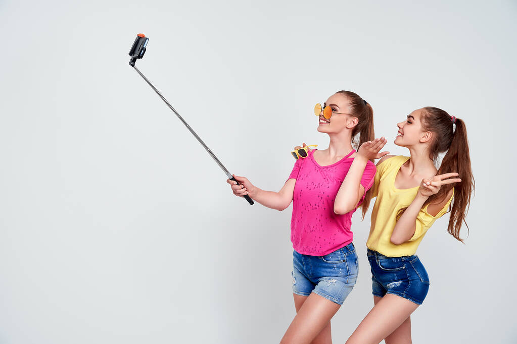 retrato de adolescentes felices tomando selfie juntos aislados en blancoRetrato de adolescentes felices en ropa de verano, gafas de sol tomando selfie juntos aislados en blanco. - Foto, imagen