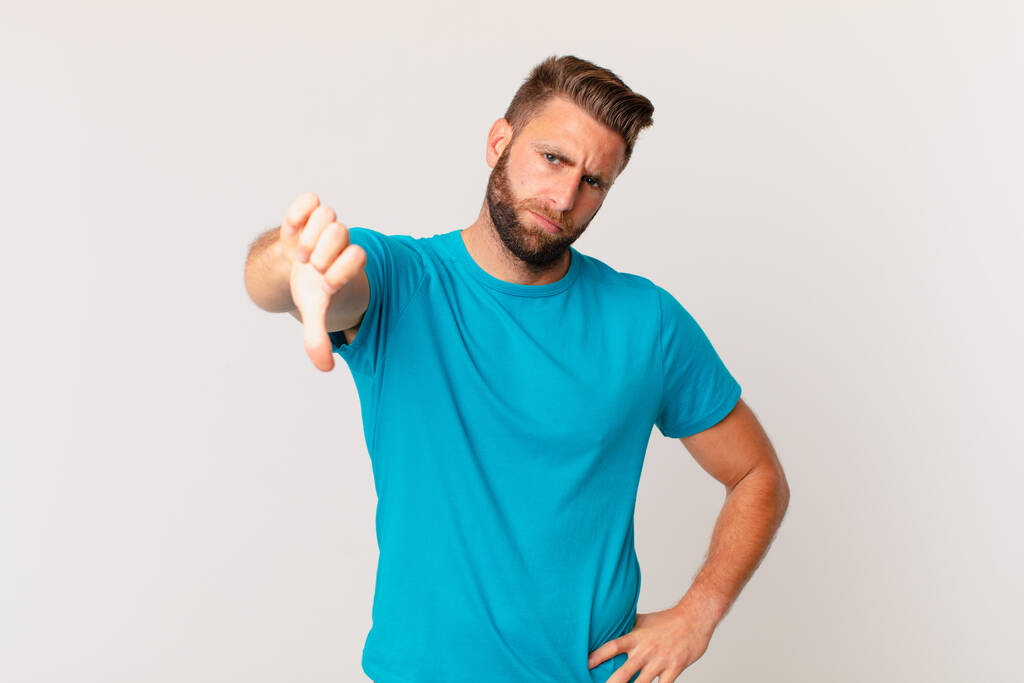 young handsome man feeling cross,showing thumbs down. fitness concept - Photo, Image