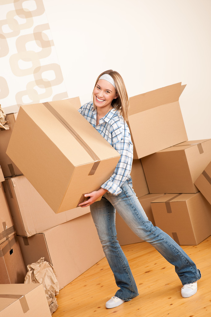 Bewegende huis: vrouw met grote kartonnen doos in nieuwe huis - Foto, afbeelding