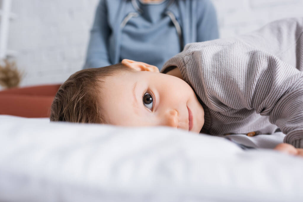 infant boy looking at camera while lying on bed  - Photo, Image