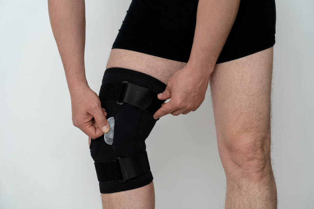 Lábtámasz. Egy férfi hozzáigazít egy fekete ortopédiát a lábához. Szélesség. - Fotó, kép