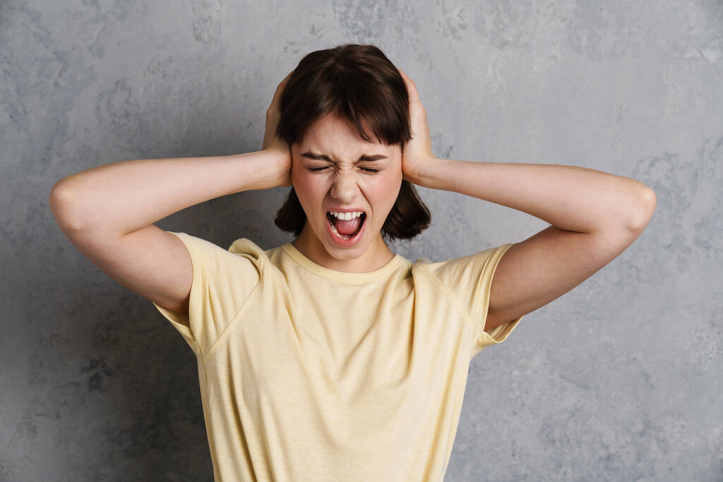 Inquiète jeune femme stressée souffrant d'une migraine isolée sur fond gris - Photo, image