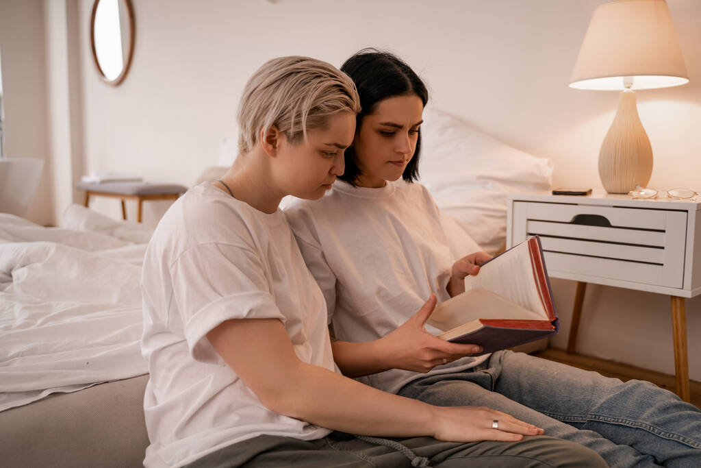 fiatal leszbikus pár olvasás könyv a hálószobában  - Fotó, kép
