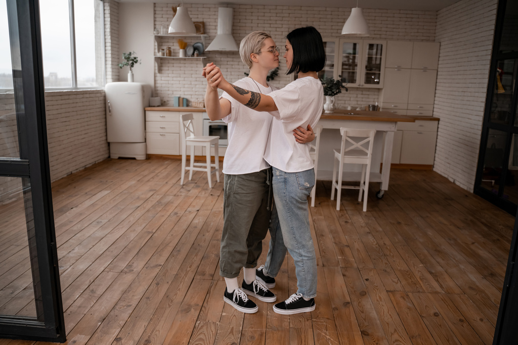 larga duración de pareja de lesbianas cogidas de la mano y bailando en la cocina  - Foto, Imagen