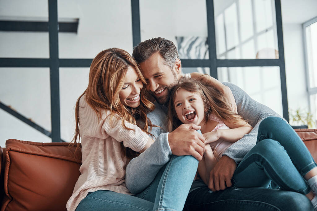gelukkig jong familie glimlachen en omarmen terwijl het verbinden van samen thuis - Foto, afbeelding