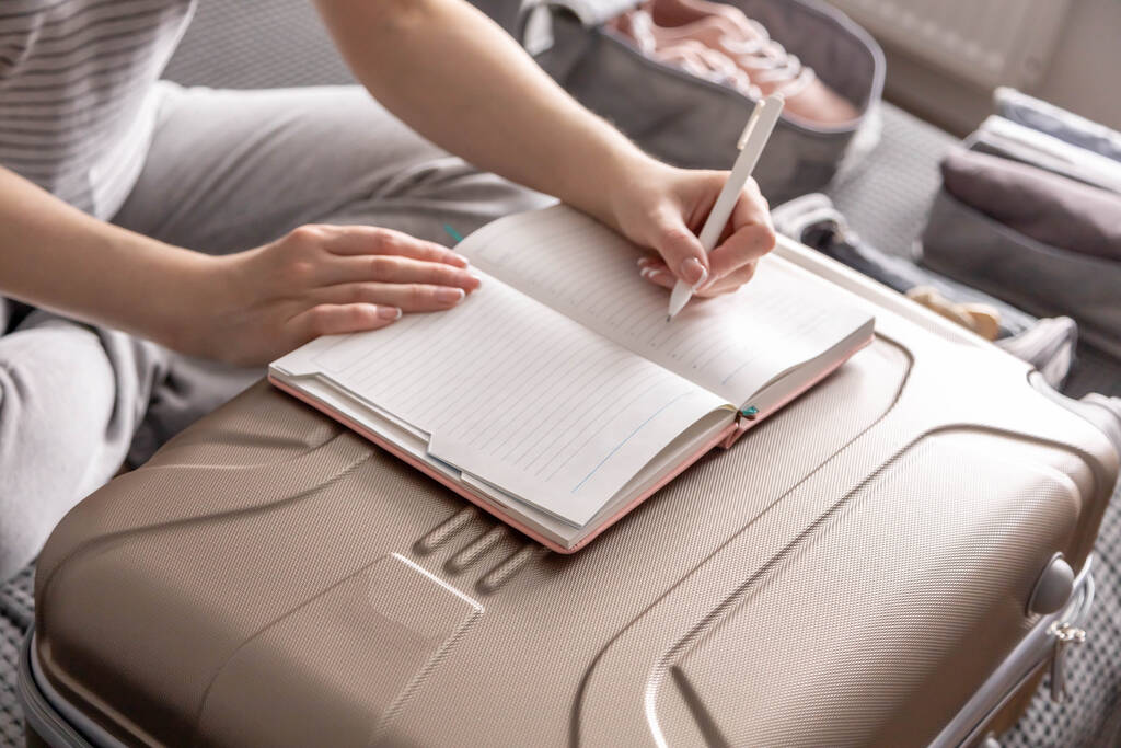 Close-up vrouwelijke handen schrijven papieren notities maken lijst van de nodige dingen om te reizen vakantie - Foto, afbeelding