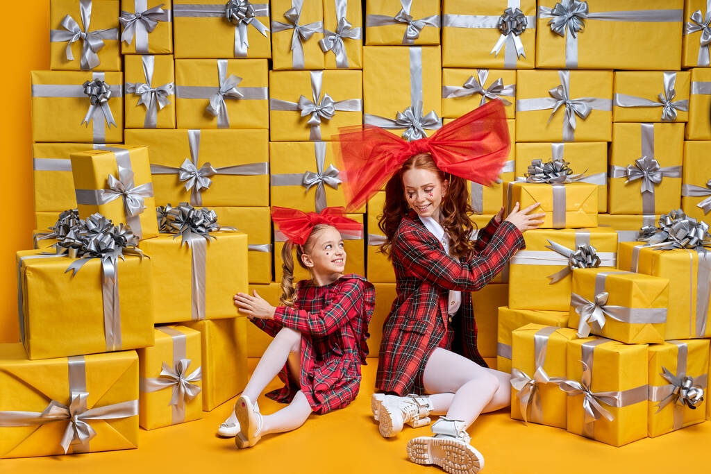 Happy mother and daughter posing near bright yellow gift boxes, unpacking - Photo, Image