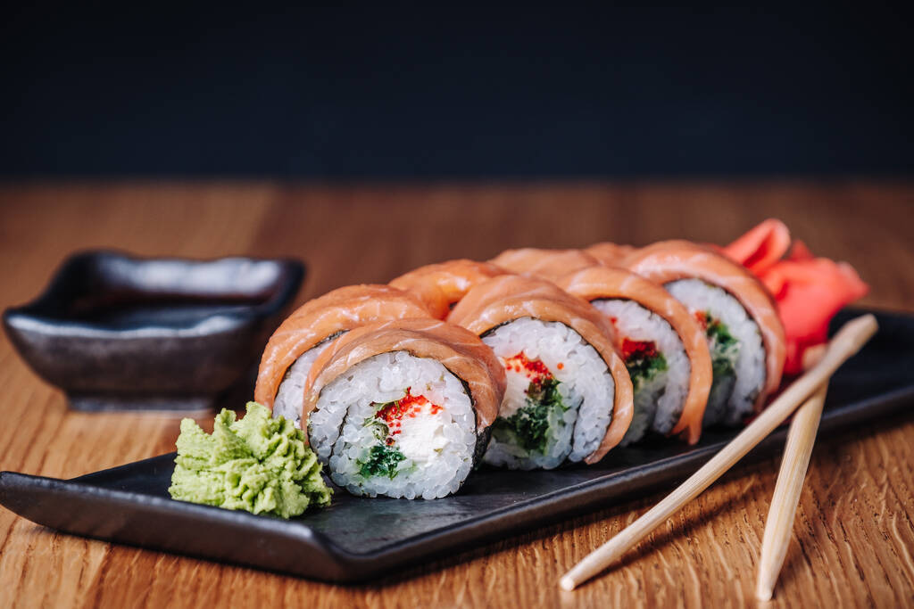 Restoranda ahşap bir masada suşi, lezzetli Japon yemekleri, suşi ruloları. - Fotoğraf, Görsel