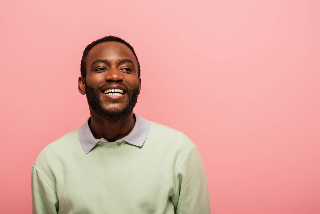 Lächelnder afrikanisch-amerikanischer Mann schaut isoliert auf rosa  - Foto, Bild