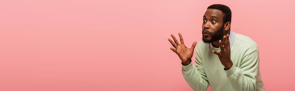 Σοκαρισμένος Αφροαμερικάνος κοιτάζει μακριά απομονωμένος σε ροζ, banner  - Φωτογραφία, εικόνα