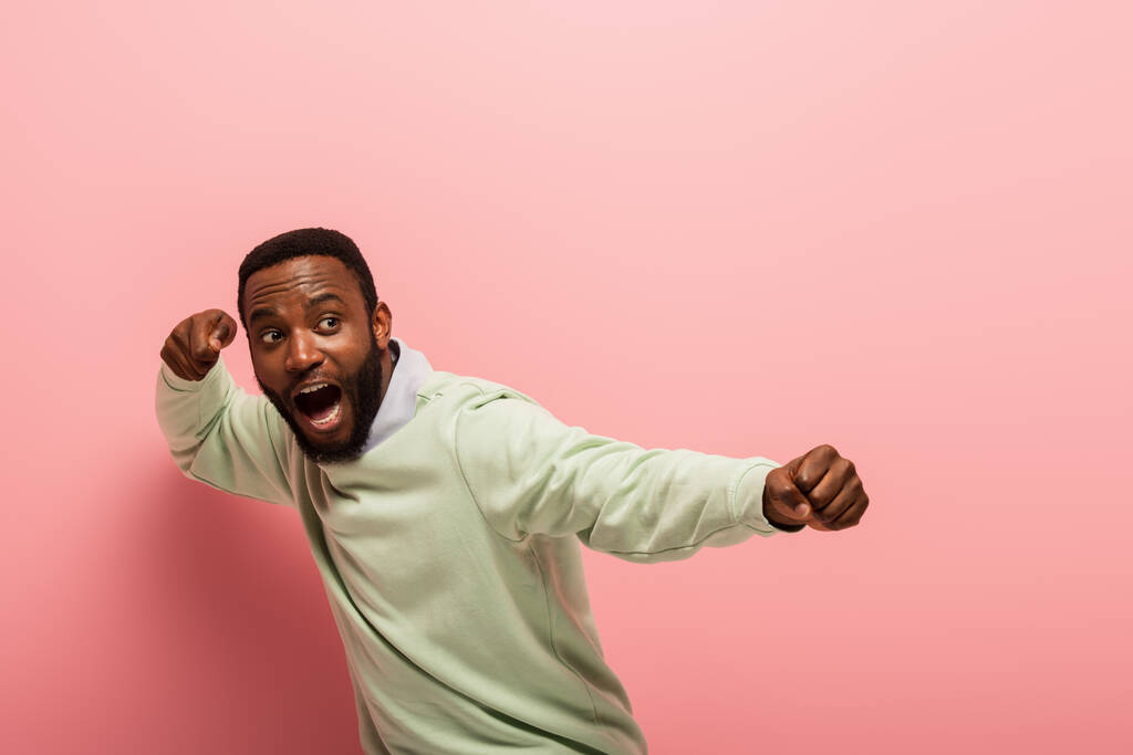 Кричащий африканский американец с кулаками на розовом фоне  - Фото, изображение
