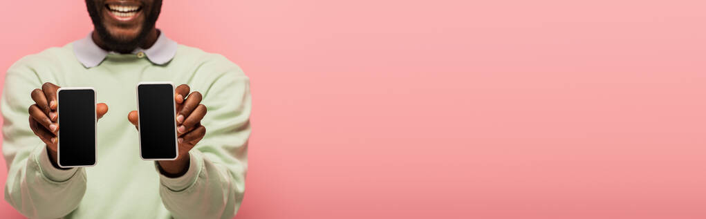 Oříznutý pohled na afrického Američana držícího smartphony izolované na růžové, banner  - Fotografie, Obrázek