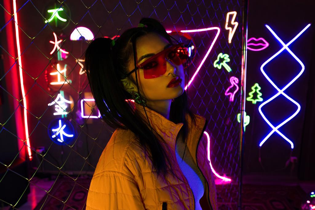 young asian woman in sunglasses looking at camera near neon sign  - Photo, Image