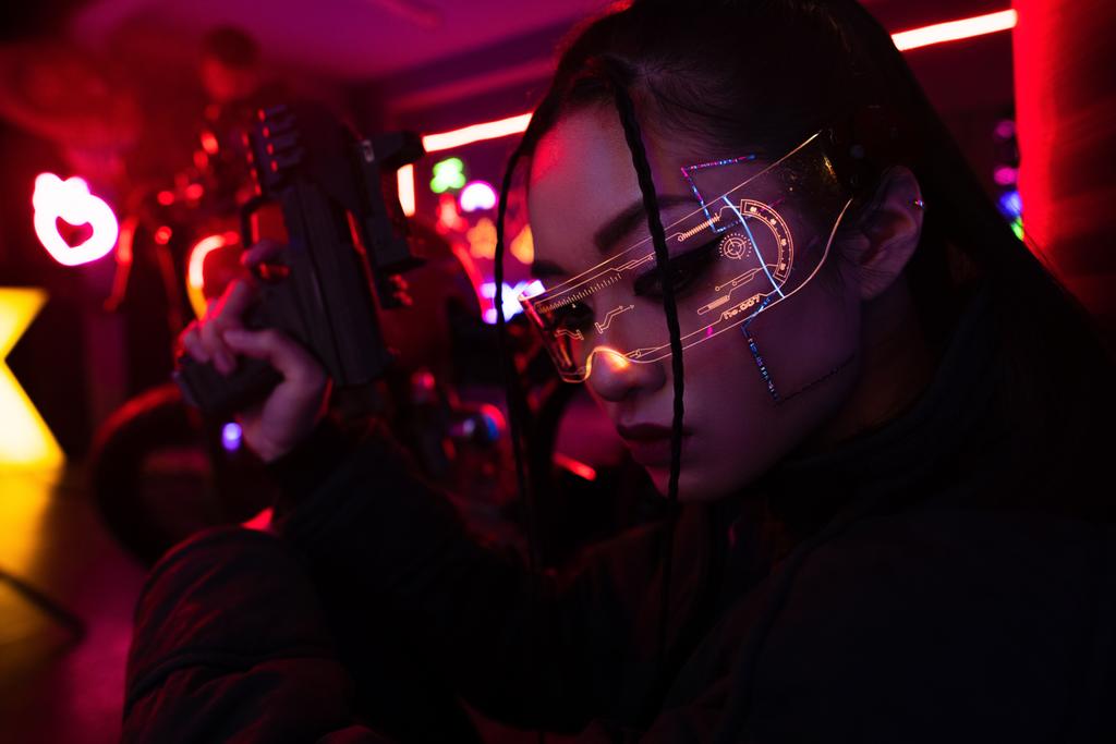 armed asian woman in sunglasses holding blurred gun outside  - 写真・画像