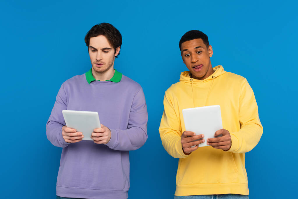 amis interracial tenant des appareils numériques avec écran blanc isolé sur bleu - Photo, image