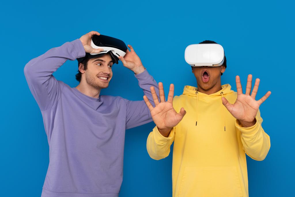 hipster interrazziale giocare con cuffie realtà virtuale isolato su blu - Foto, immagini