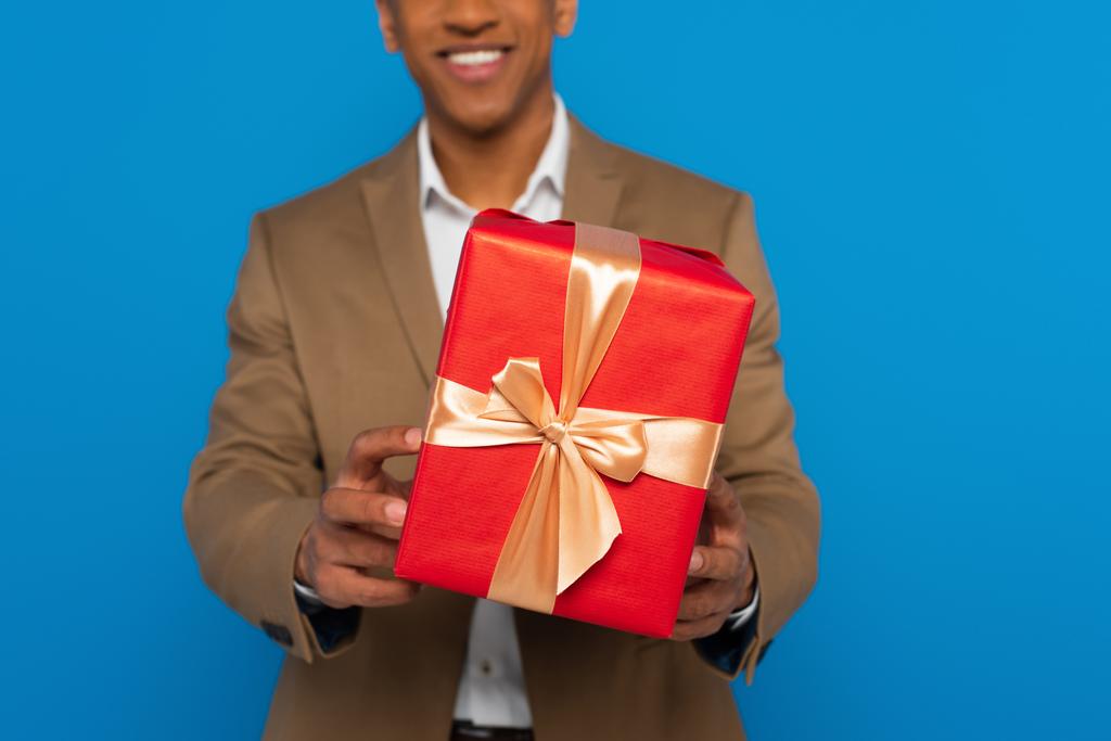 przycięty widok młodych afrykańskich mężczyzn ramiona prezentuje pudełko prezent odizolowany na niebiesko - Zdjęcie, obraz