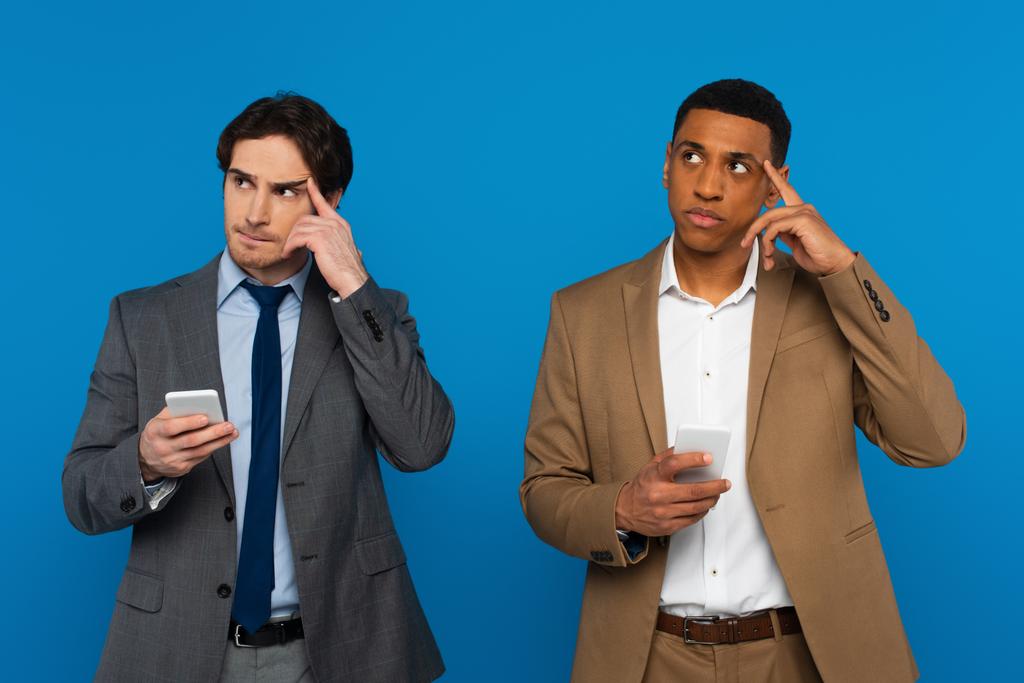 elmélkedő fajok közötti férfiak figyelmes gesztussal okostelefonokat tartanak a kezükben elszigetelve a kék - Fotó, kép