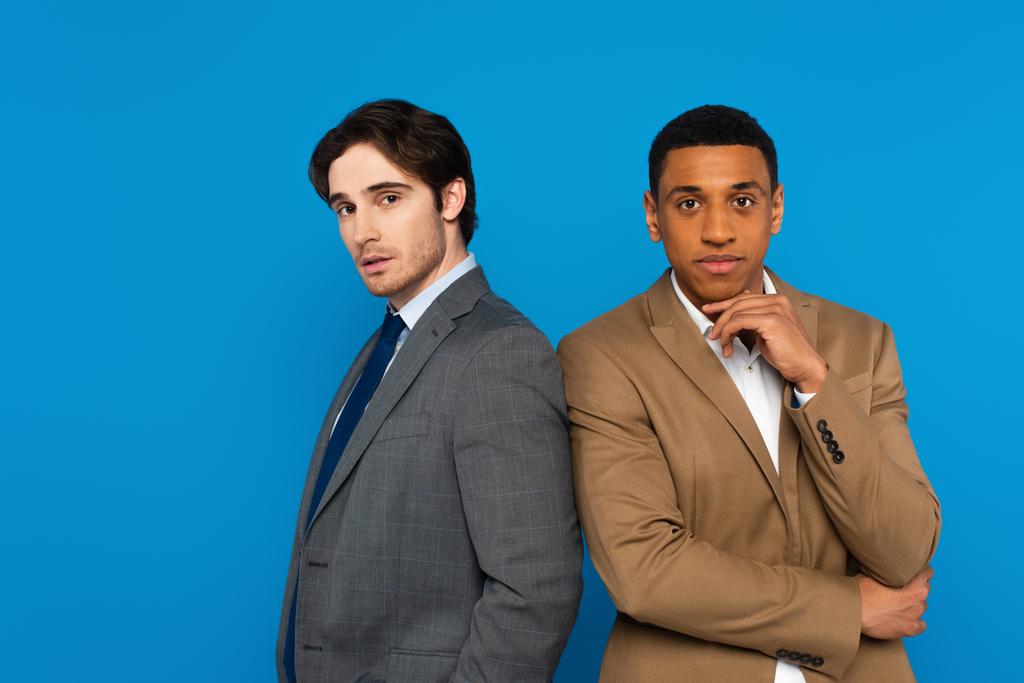 elegante interracial homens no ternos pé juntos isolado no azul - Foto, Imagem