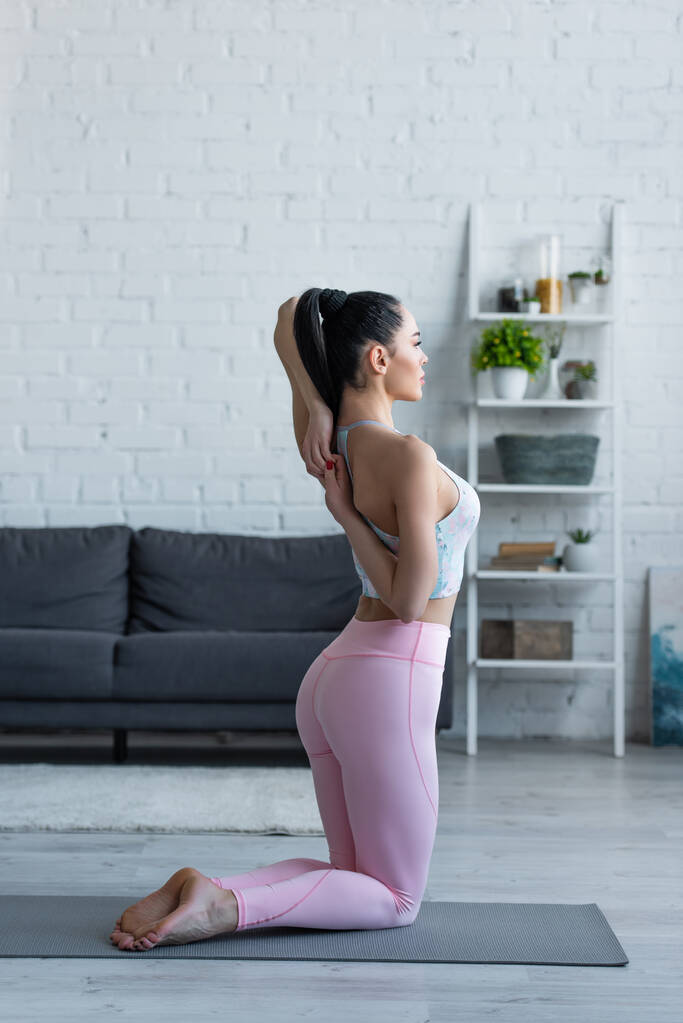 sportive woman practicing yoga in kneeling pose with hands behind back - Photo, Image