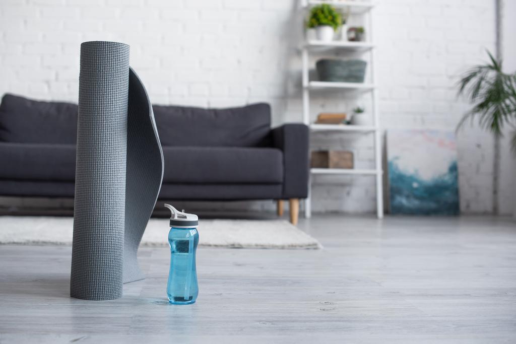 rolled fitness mat near sports bottle with water on blurred background - Photo, Image