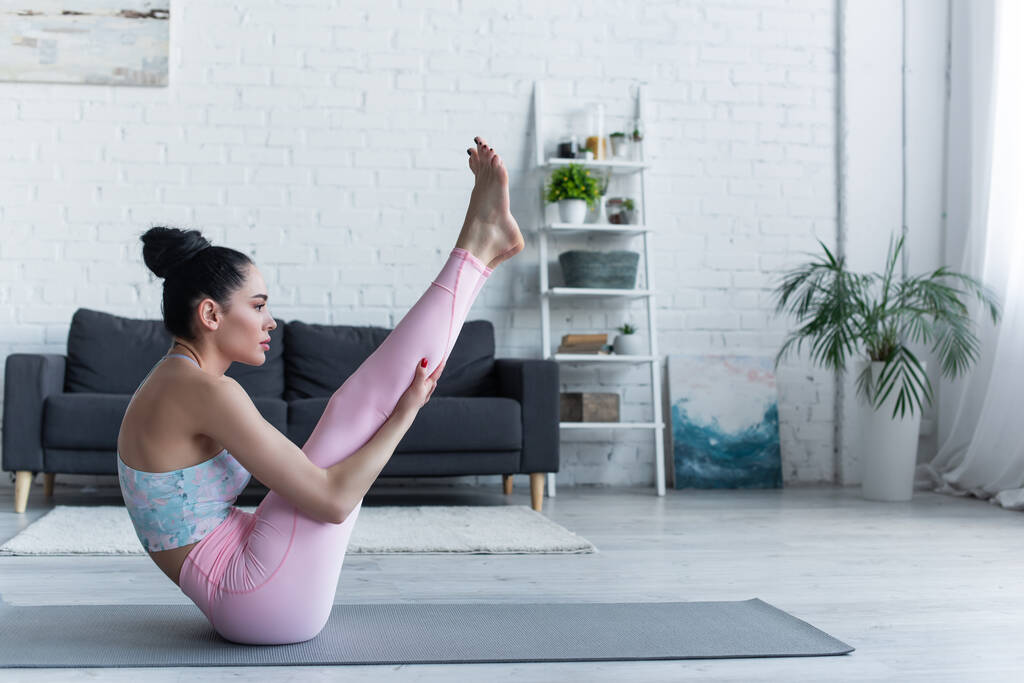 side view of brunette woman practicing yoga in boat pose at home - Photo, Image