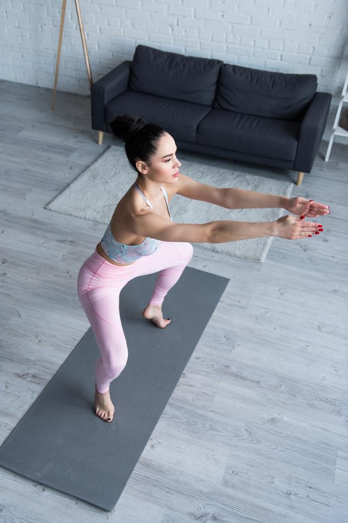 vista de ángulo alto de la mujer descalza en postura incómoda en la esterilla de yoga - Foto, imagen