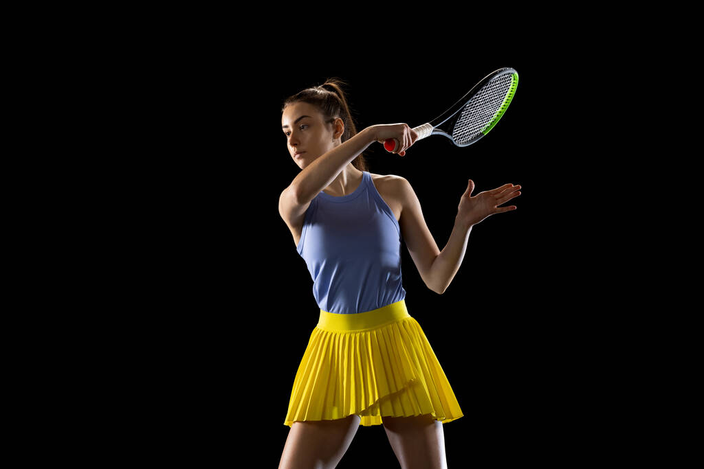 Nuori valkoihoinen nainen pelaa tennistä eristetty musta studio tausta toiminnassa ja liike, urheilu käsite - Valokuva, kuva