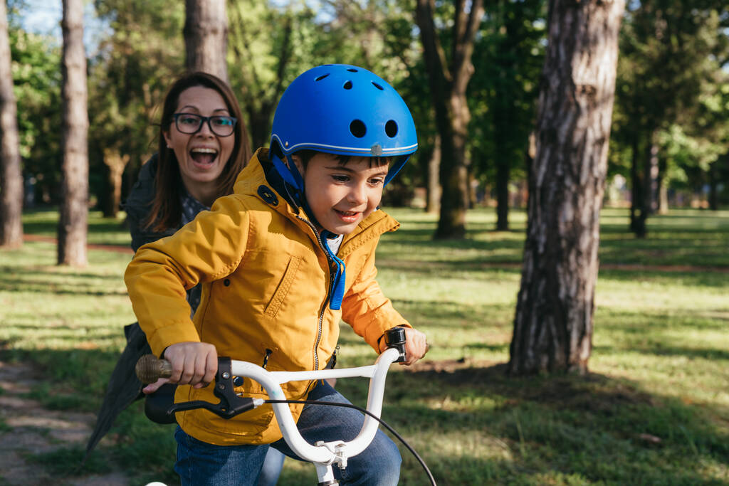 Mutter hilft ihrem Sohn beim Fahrradfahren - Foto, Bild